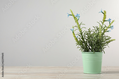 Beautiful artificial plant in flower pot on wooden table against light grey background  space for text