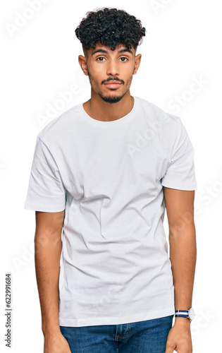 Young arab man wearing casual white t shirt looking sleepy and tired, exhausted for fatigue and hangover, lazy eyes in the morning.