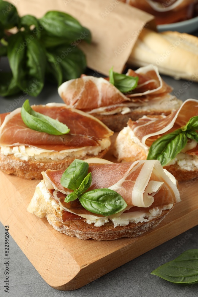 Tasty sandwiches with cured ham and basil on grey table, closeup Tasty sandwiches with cured ham and basil on grey table, closeup