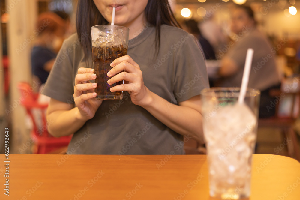 Woman drinking soft drink from the glass in the restaurant. sugary drinks, Unhealthy diet, sweet sugary soft drinks, coke, freshness concept