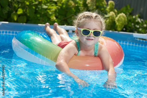 Little girl swimming and relax in a blue pool on an inflatable ring