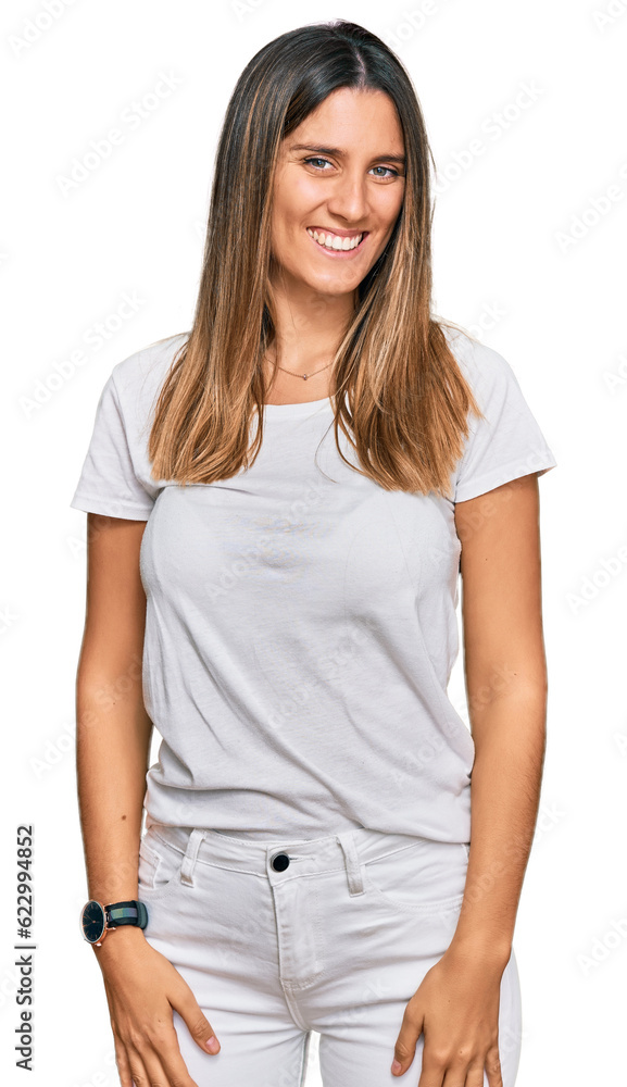 Young woman wearing casual white t shirt looking positive and happy standing and smiling with a confident smile showing teeth Young woman wearing casual white t shirt looking positive and happy standing and smiling with a confident smile showing teeth