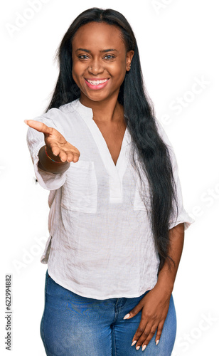 Fotografie Young black woman wearing casual clothes smiling friendly offering handshake as greeting and welcoming