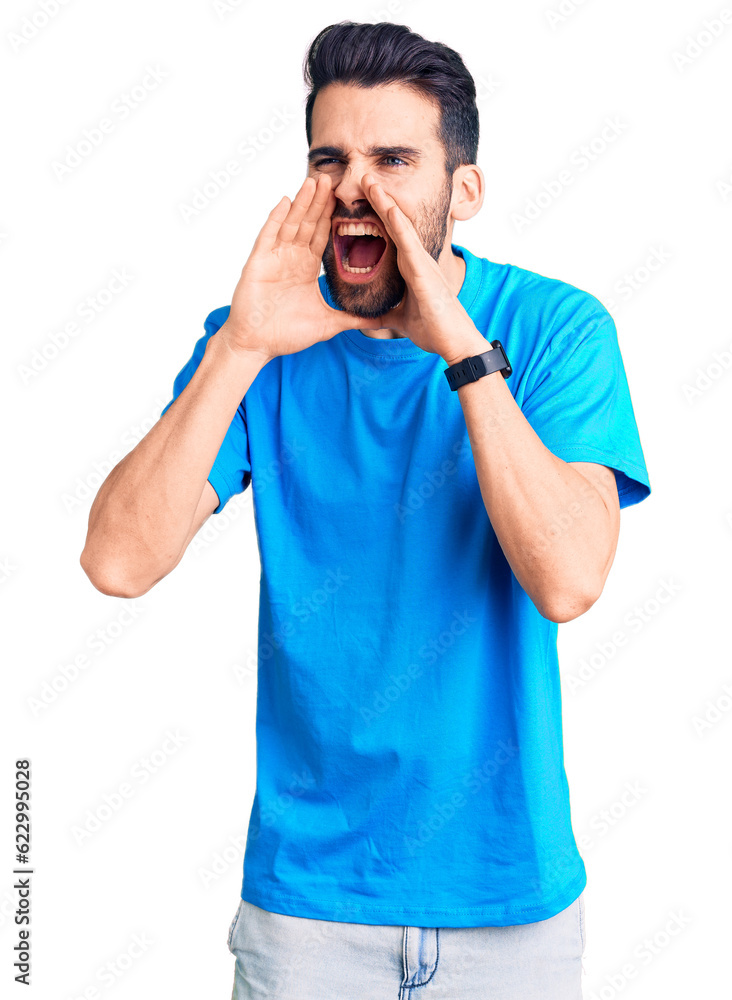 Young handsome man with beard wearing casual t-shirt shouting angry out loud with hands over mouth