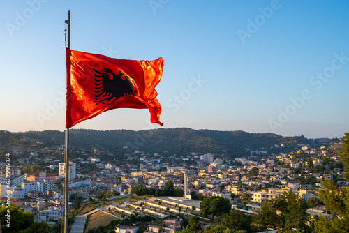Albania flag. Albanian flag on a flagpole waving on a bright blue sky background