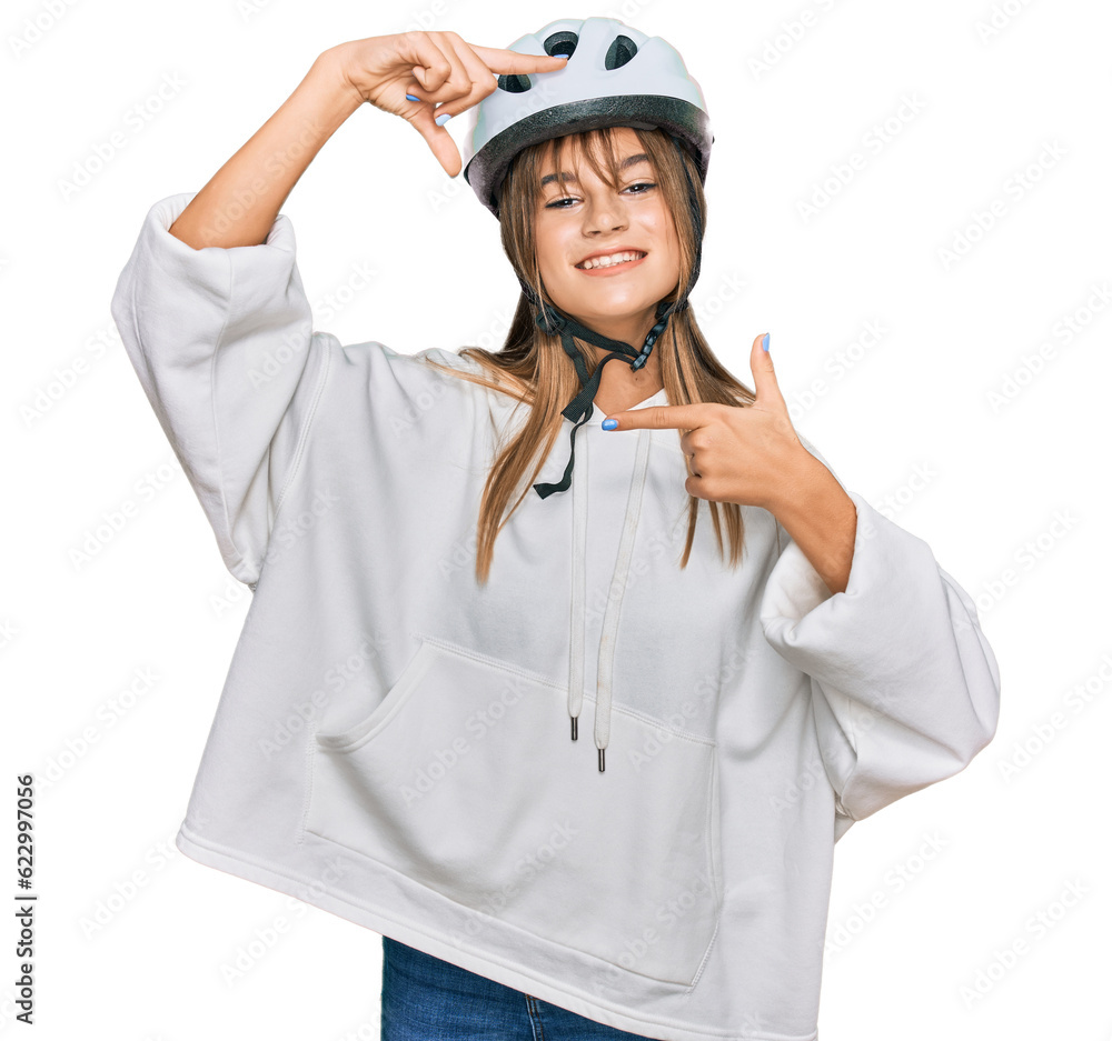 Teenager caucasian girl wearing bike helmet smiling making frame with hands and fingers with happy face. creativity and photography concept. Teenager caucasian girl wearing bike helmet smiling making frame with hands and fingers with happy face. creativity and photography concept.