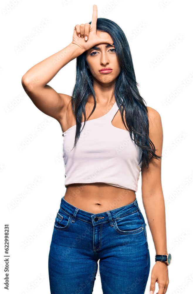 Beautiful hispanic woman wearing casual clothes making fun of people with fingers on forehead doing loser gesture mocking and insulting. Beautiful hispanic woman wearing casual clothes making fun of people with fingers on forehead doing loser gesture mocking and insulting.