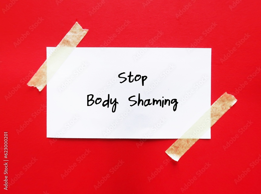 Note stick on red background with handwritten text STOP BODY SHAMING ...
