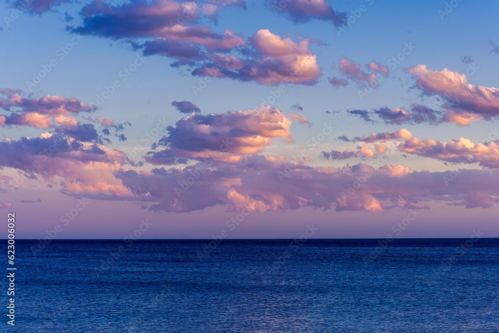 scenic blue seascape of sunset or sunrise above water with beautiful colorful evening clouds