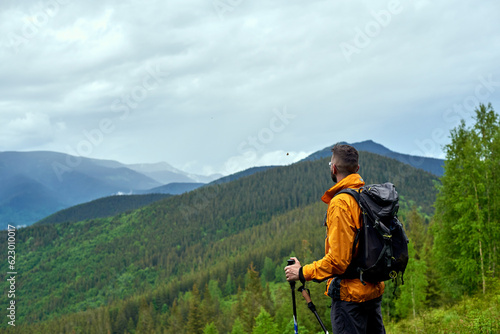 Hiker with trekking sticks enjoying mountains view Resting and breathing. Activity and sport concept...
