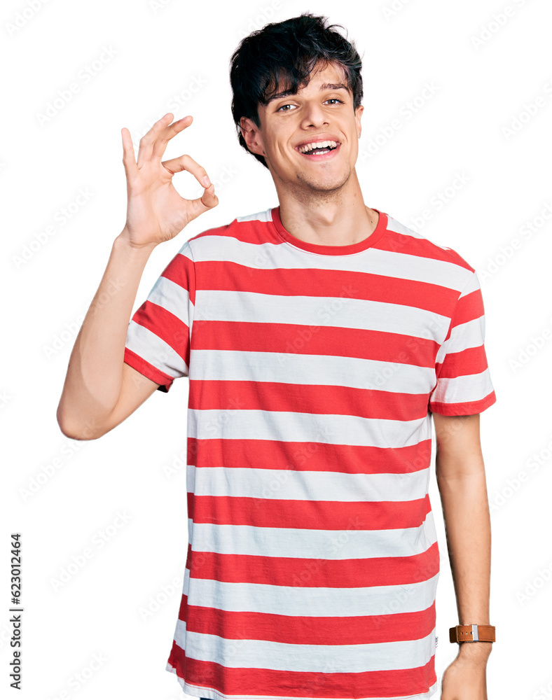 Handsome hipster young man wearing casual striped t shirt smiling positive doing ok sign with hand and fingers. successful expression. Handsome hipster young man wearing casual striped t shirt smiling positive doing ok sign with hand and fingers. successful expression.