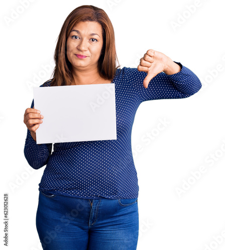 Canvastavla Middle age latin woman holding paper banner with blank space with angry face, ne