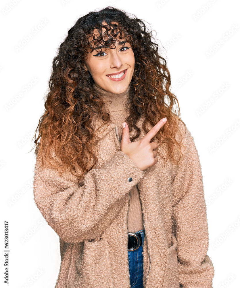 Young hispanic girl wearing winter clothes cheerful with a smile of face pointing with hand and finger up to the side with happy and natural expression on face Young hispanic girl wearing winter clothes cheerful with a smile of face pointing with hand and finger up to the side with happy and natural expression on face