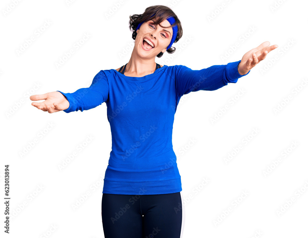 Beautiful young woman with short hair wearing training workout clothes smiling cheerful offering hands giving assistance and acceptance. Beautiful young woman with short hair wearing training workout clothes smiling cheerful offering hands giving assistance and acceptance.