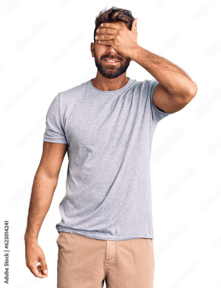 Young hispanic man wearing casual clothes smiling and laughing with hand on face covering eyes for surprise. blind concept. Young hispanic man wearing casual clothes smiling and laughing with hand on face covering eyes for surprise. blind concept.