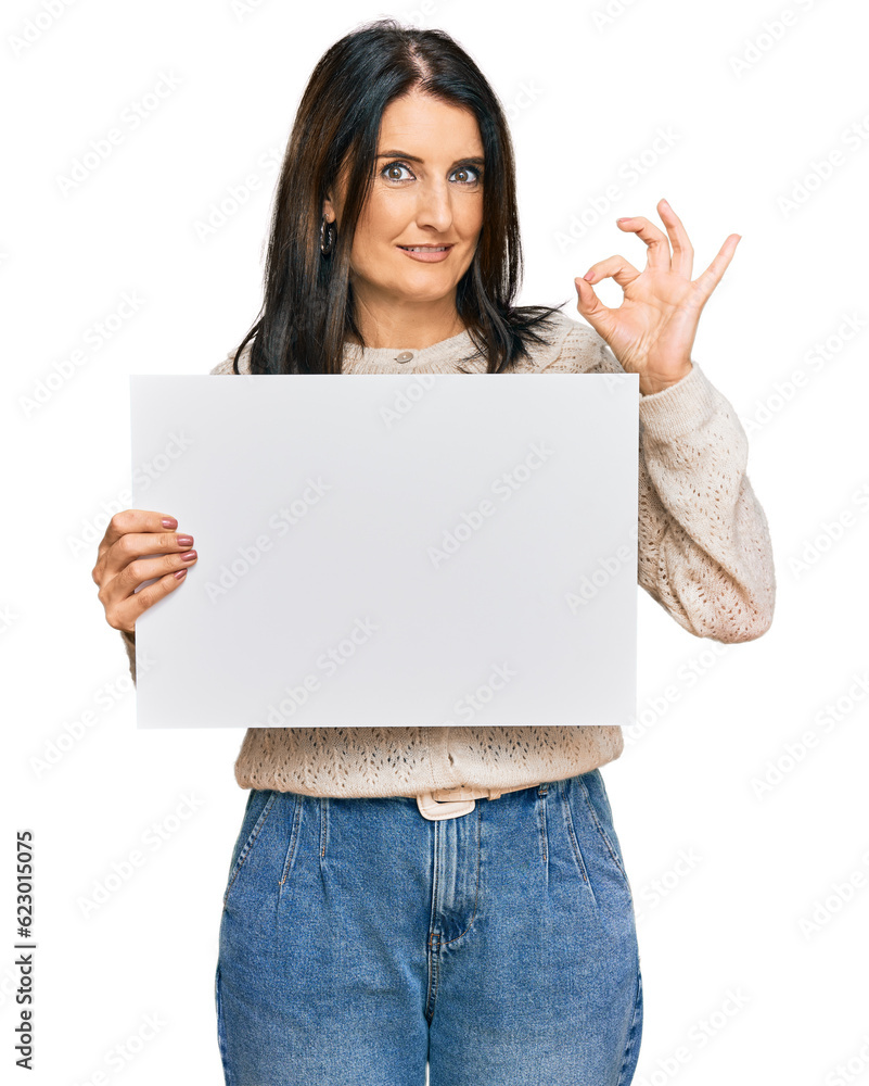 Middle age brunette woman holding blank empty banner doing ok sign with fingers, smiling friendly gesturing excellent symbol Middle age brunette woman holding blank empty banner doing ok sign with fingers, smiling friendly gesturing excellent symbol