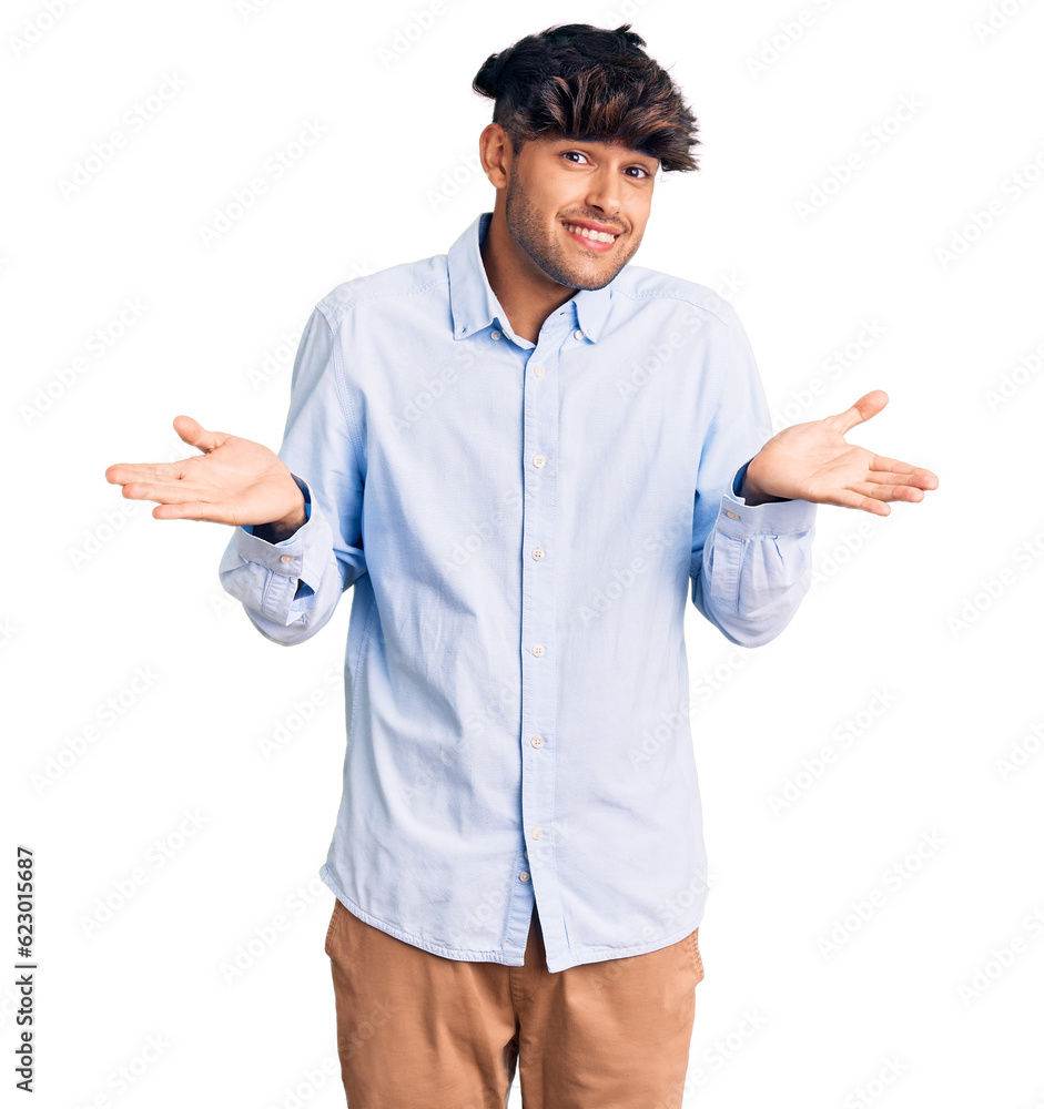 Young hispanic man wearing casual shirt clueless and confused expression with arms and hands raised. doubt concept.