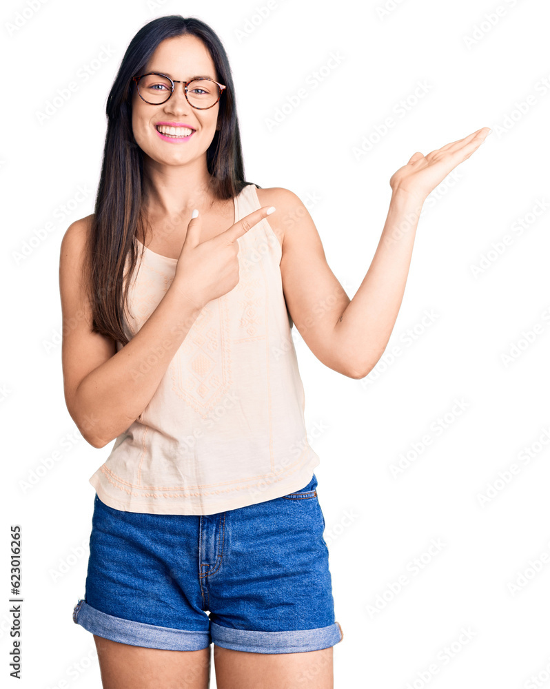 Young beautiful caucasian woman wearing casual clothes and glasses amazed and smiling to the camera while presenting with hand and pointing with finger. Young beautiful caucasian woman wearing casual clothes and glasses amazed and smiling to the camera while presenting with hand and pointing with finger.