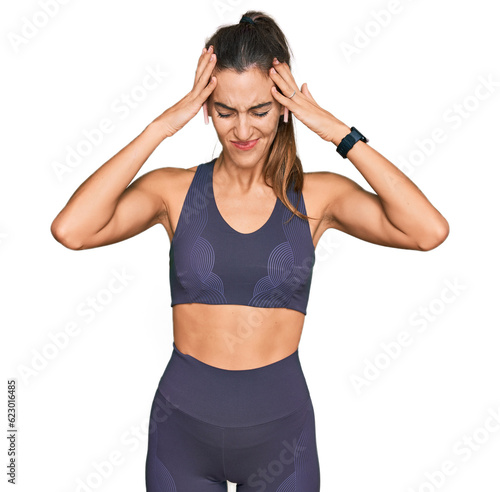 Young beautiful woman wearing sportswear suffering from headache desperate and stressed because pain and migraine. hands on head. © Krakenimages.com