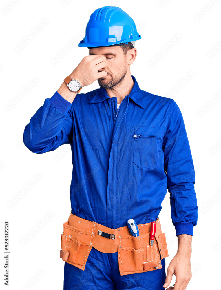 Young handsome man wearing worker uniform and hardhat strong person showing arm muscle, confident and proud of power Young handsome man wearing worker uniform and hardhat strong person showing arm muscle, confident and proud of power