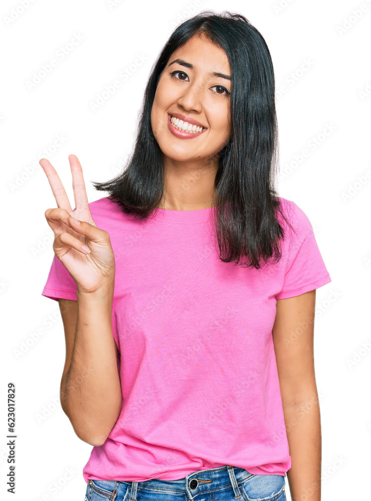 Beautiful asian young woman wearing casual pink t shirt showing and pointing up with fingers number two while smiling confident and happy. Beautiful asian young woman wearing casual pink t shirt showing and pointing up with fingers number two while smiling confident and happy.