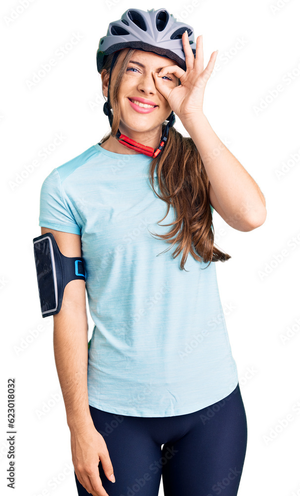 Beautiful caucasian young woman wearing bike helmet smiling happy doing ok sign with hand on eye looking through fingers Beautiful caucasian young woman wearing bike helmet smiling happy doing ok sign with hand on eye looking through fingers