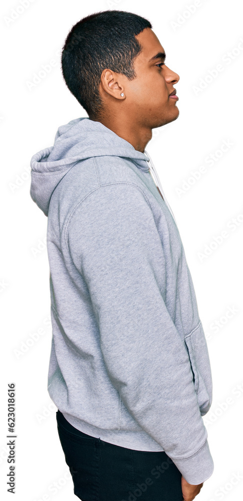 Young handsome hispanic man wearing casual sweatshirt looking to side, relax profile pose with natural face with confident smile.