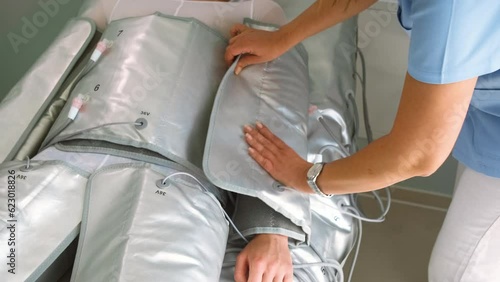 Beautician therapist applying pressotherapy treatment beauty salon to young man.