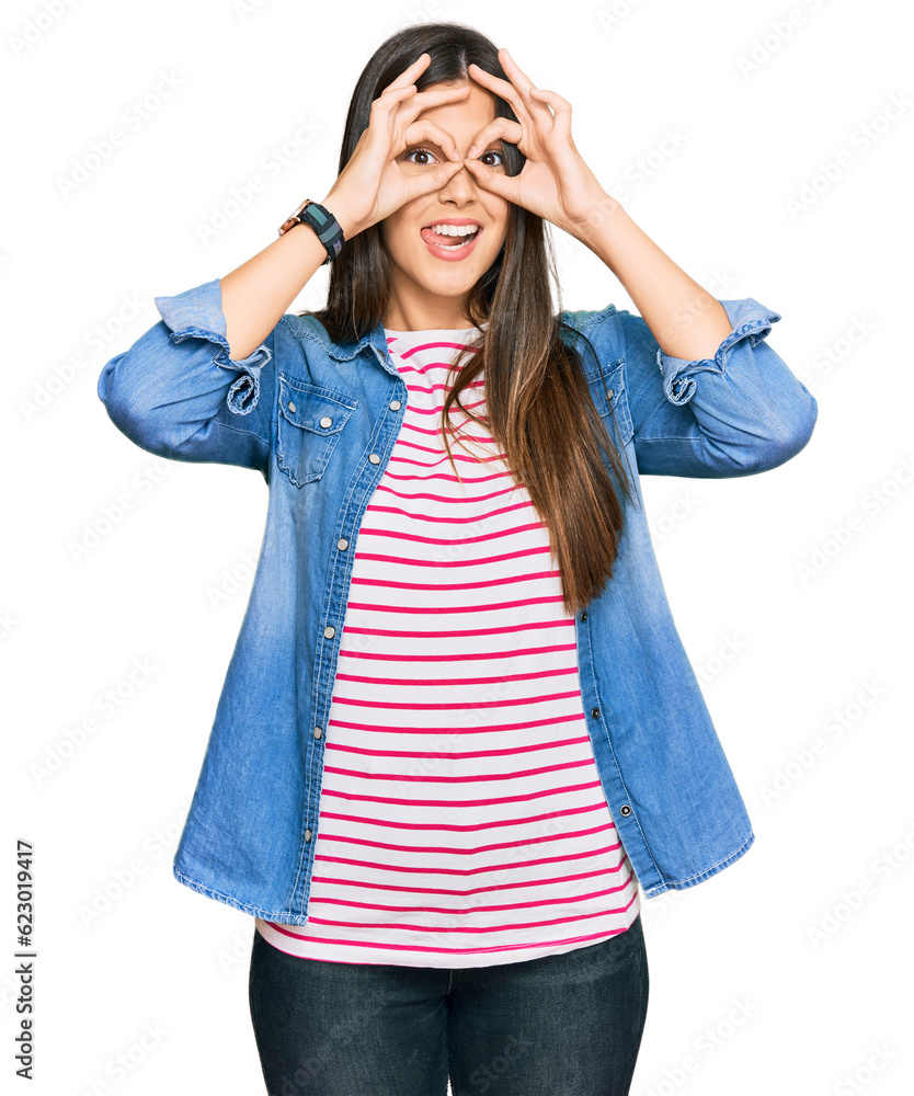 Young brunette woman wearing casual clothes doing ok gesture like binoculars sticking tongue out, eyes looking through fingers. crazy expression. Young brunette woman wearing casual clothes doing ok gesture like binoculars sticking tongue out, eyes looking through fingers. crazy expression.