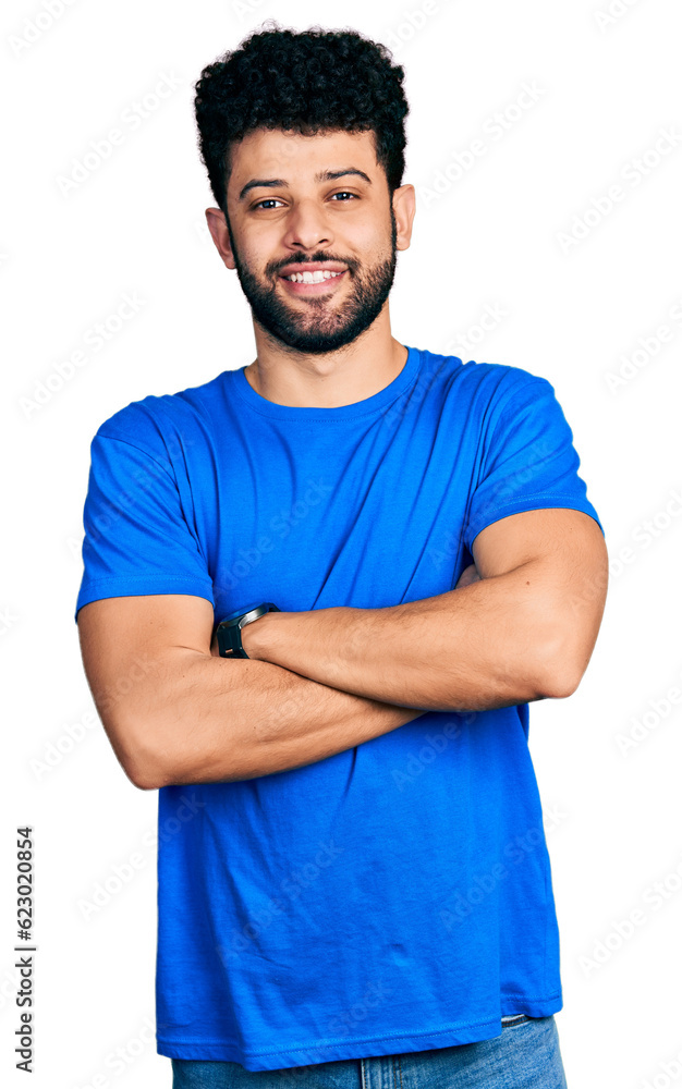 Young arab man with beard wearing casual blue t shirt happy face smiling with crossed arms looking at the camera. positive person. Young arab man with beard wearing casual blue t shirt happy face smiling with crossed arms looking at the camera. positive person.