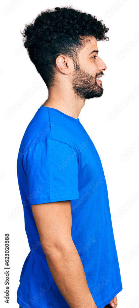 Young arab man with beard wearing casual blue t shirt looking to side, relax profile pose with natural face and confident smile.