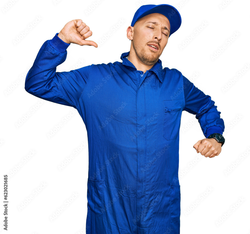 Bald man with beard wearing builder jumpsuit uniform stretching back, tired and relaxed, sleepy and yawning for early morning Bald man with beard wearing builder jumpsuit uniform stretching back, tired and relaxed, sleepy and yawning for early morning