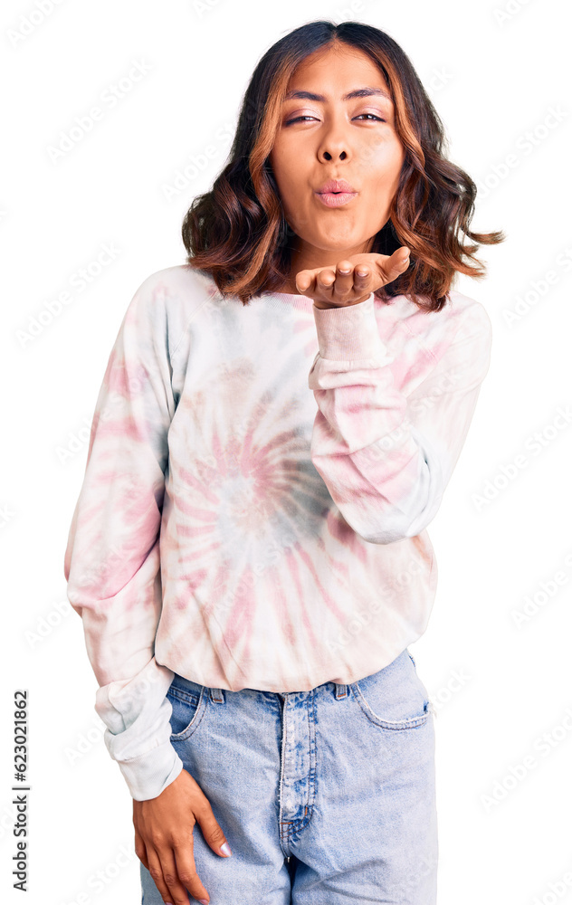 Young beautiful mixed race woman wearing casual tie dye sweatshirt looking at the camera blowing a kiss with hand on air being lovely and sexy. love expression. Young beautiful mixed race woman wearing casual tie dye sweatshirt looking at the camera blowing a kiss with hand on air being lovely and sexy. love expression.