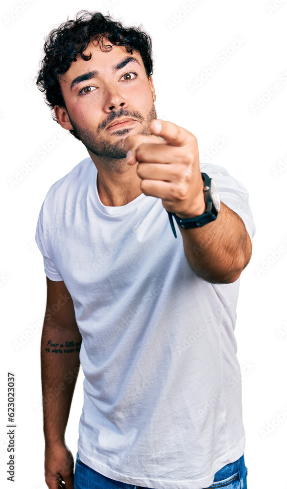 Hispanic young man with beard wearing casual white t shirt pointing displeased and frustrated to the camera, angry and furious with you Hispanic young man with beard wearing casual white t shirt pointing displeased and frustrated to the camera, angry and furious with you