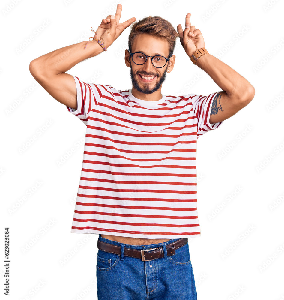 Handsome blond man with beard wearing casual clothes and glasses posing funny and crazy with fingers on head as bunny ears, smiling cheerful Handsome blond man with beard wearing casual clothes and glasses posing funny and crazy with fingers on head as bunny ears, smiling cheerful