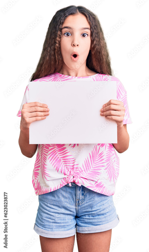 Cute hispanic child girl holding blank empty banner scared and amazed with open mouth for surprise, disbelief face Cute hispanic child girl holding blank empty banner scared and amazed with open mouth for surprise, disbelief face