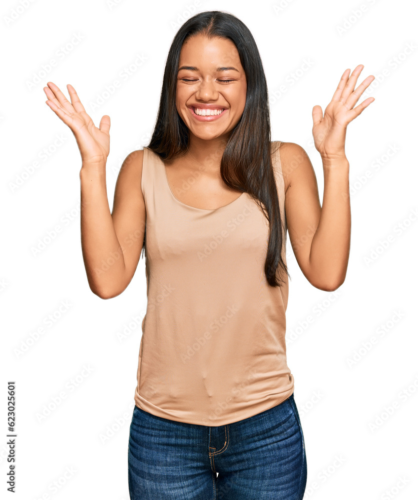 Beautiful hispanic woman wearing casual clothes celebrating mad and crazy for success with arms raised and closed eyes screaming excited. winner concept Beautiful hispanic woman wearing casual clothes celebrating mad and crazy for success with arms raised and closed eyes screaming excited. winner concept