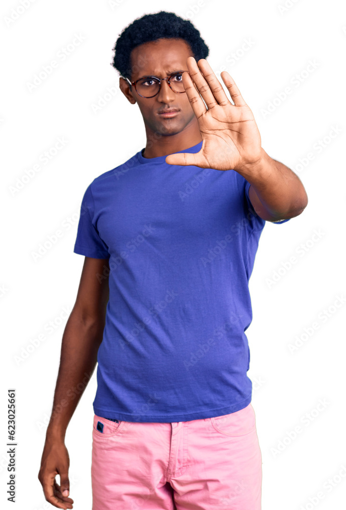 Fototapeta premium African handsome man wearing casual clothes and glasses doing stop sing with palm of the hand. warning expression with negative and serious gesture on the face.
