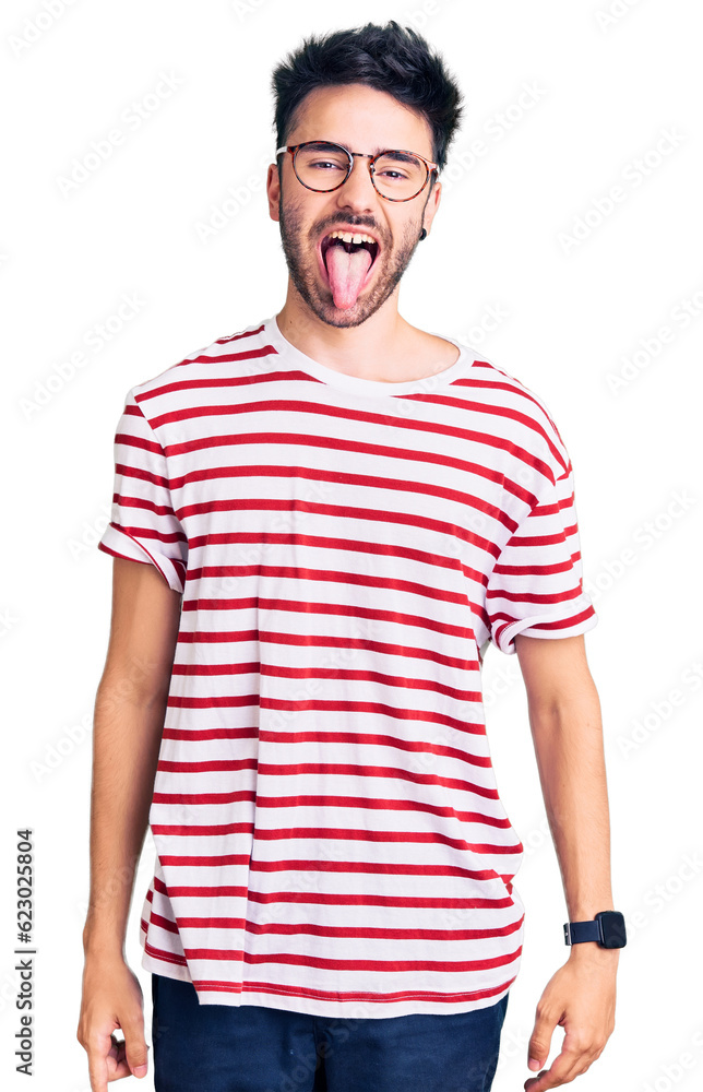 Young hispanic man wearing casual clothes sticking tongue out happy with funny expression. emotion concept. Young hispanic man wearing casual clothes sticking tongue out happy with funny expression. emotion concept.