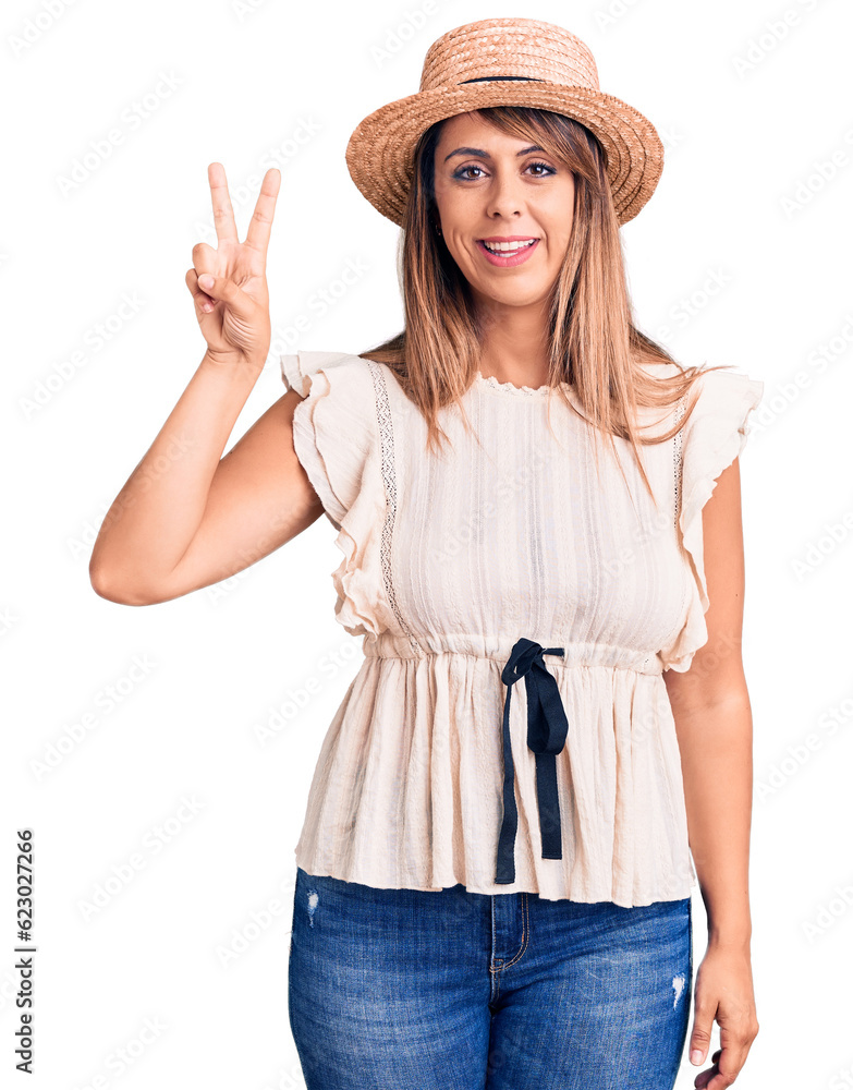 Young beautiful woman wearing summer hat and t-shirt showing and pointing up with fingers number two while smiling confident and happy. Young beautiful woman wearing summer hat and t-shirt showing and pointing up with fingers number two while smiling confident and happy.