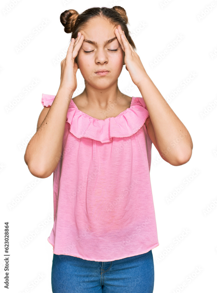 Beautiful brunette little girl wearing summer pink shirt suffering from headache desperate and stressed because pain and migraine. hands on head. Beautiful brunette little girl wearing summer pink shirt suffering from headache desperate and stressed because pain and migraine. hands on head.
