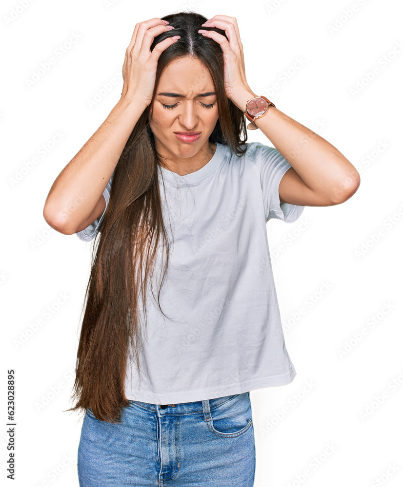 Young hispanic girl wearing casual white t shirt suffering from headache desperate and stressed because pain and migraine. hands on head. Young hispanic girl wearing casual white t shirt suffering from headache desperate and stressed because pain and migraine. hands on head.