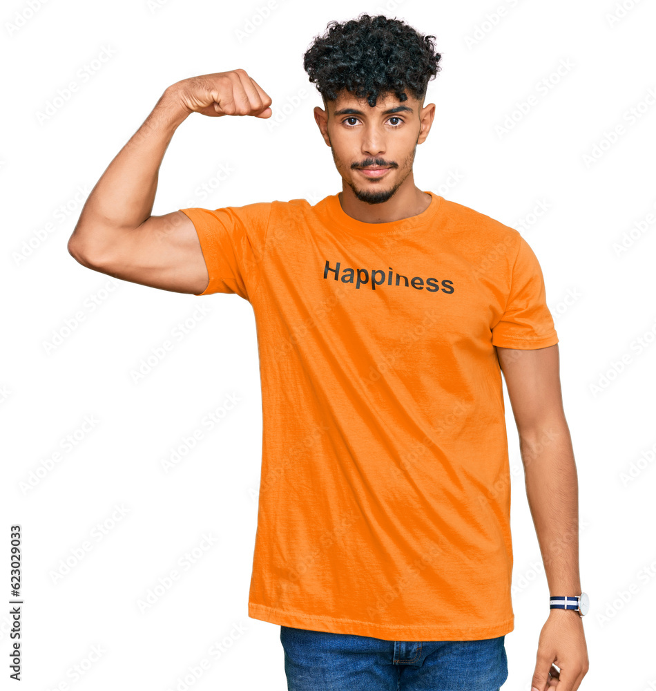 Young arab man wearing tshirt with happiness word message strong person showing arm muscle, confident and proud of power Young arab man wearing tshirt with happiness word message strong person showing arm muscle, confident and proud of power