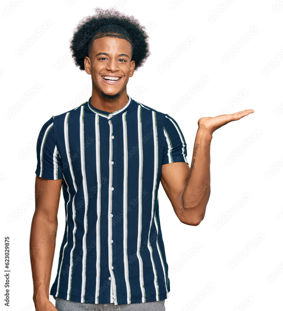 African american man with afro hair wearing casual clothes smiling cheerful presenting and pointing with palm of hand looking at the camera. African american man with afro hair wearing casual clothes smiling cheerful presenting and pointing with palm of hand looking at the camera.