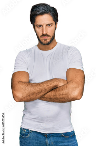 Young hispanic man wearing casual white t shirt skeptic and nervous, disapproving expression on face with crossed arms. negative person.