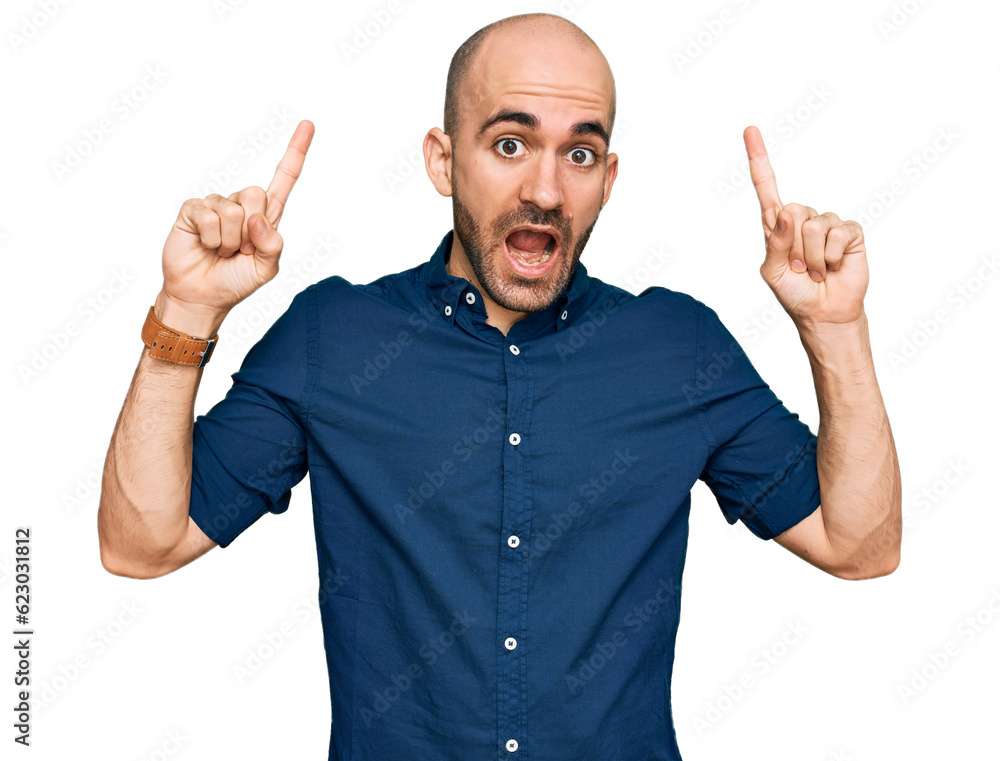 Young hispanic man wearing casual clothes smiling amazed and surprised and pointing up with fingers and raised arms. Young hispanic man wearing casual clothes smiling amazed and surprised and pointing up with fingers and raised arms.