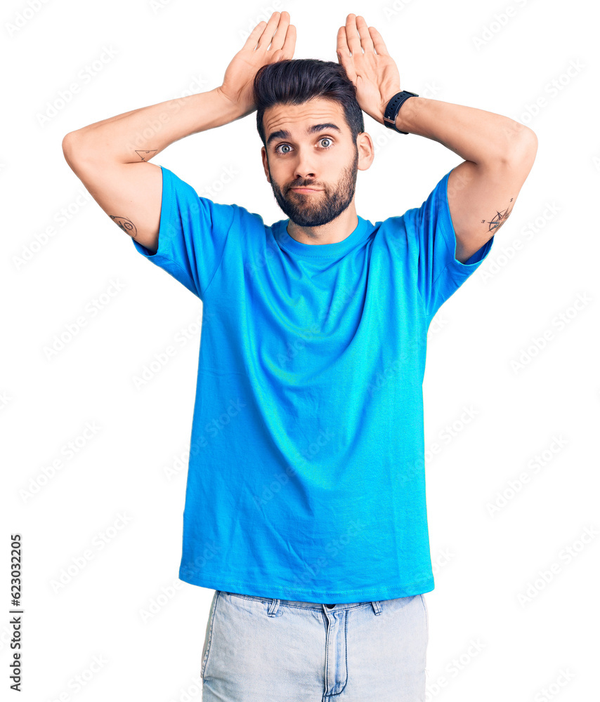 Young handsome man with beard wearing casual t-shirt doing bunny ears gesture with hands palms looking cynical and skeptical. easter rabbit concept. Young handsome man with beard wearing casual t-shirt doing bunny ears gesture with hands palms looking cynical and skeptical. easter rabbit concept.