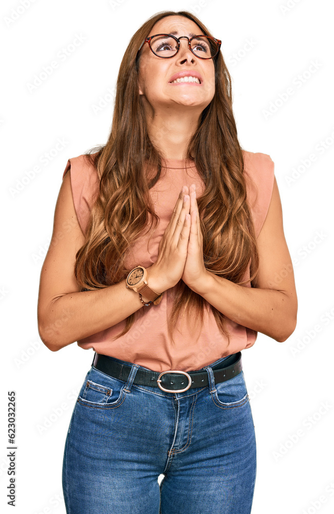 Young hispanic woman wearing casual clothes and glasses begging and praying with hands together with hope expression on face very emotional and worried. begging. Young hispanic woman wearing casual clothes and glasses begging and praying with hands together with hope expression on face very emotional and worried. begging.