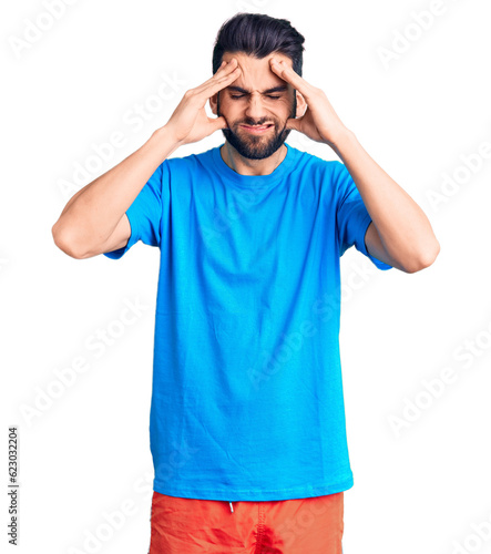Young handsome man with beard wearing casual t-shirt suffering from headache desperate and stressed because pain and migraine. hands on head.