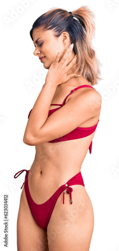 Young beautiful woman wearing bikini suffering of neck ache injury, touching neck with hand, muscular pain